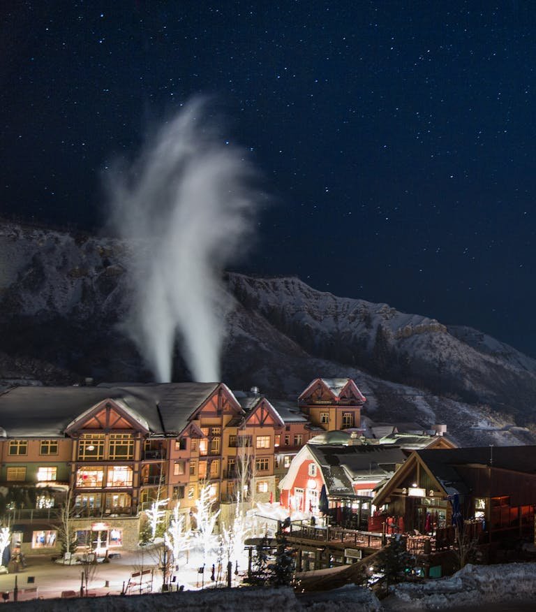 Charming winter night scene in Snowmass Village with snow-covered buildings under a starry sky.