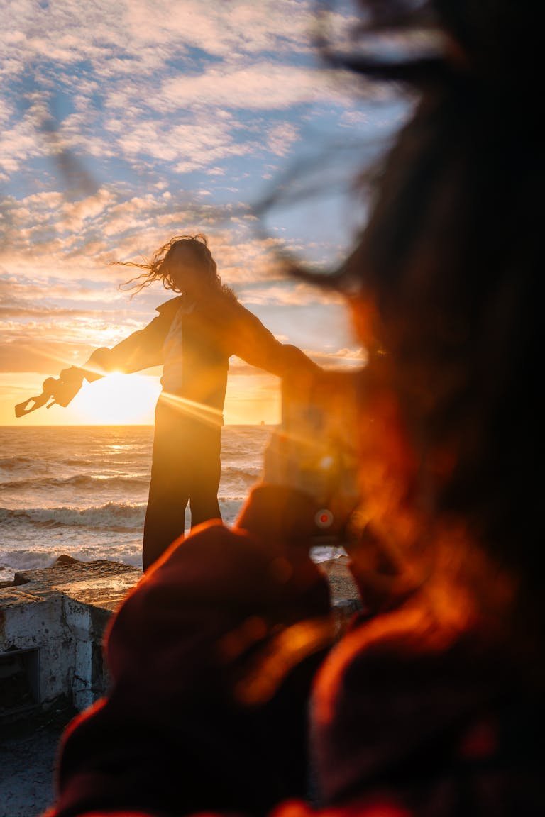 Silhouette of a person at sunset by the ocean, capturing a serene moment.