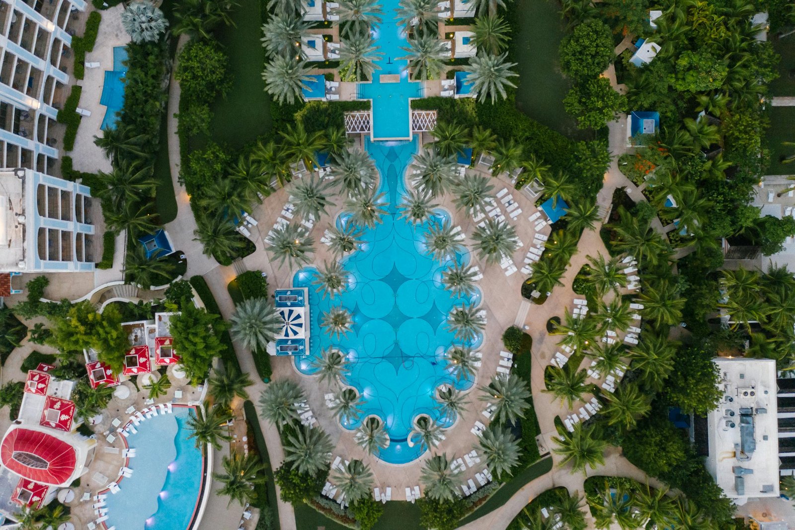Aerial view of a luxury resort featuring expansive pools and lush palm trees.